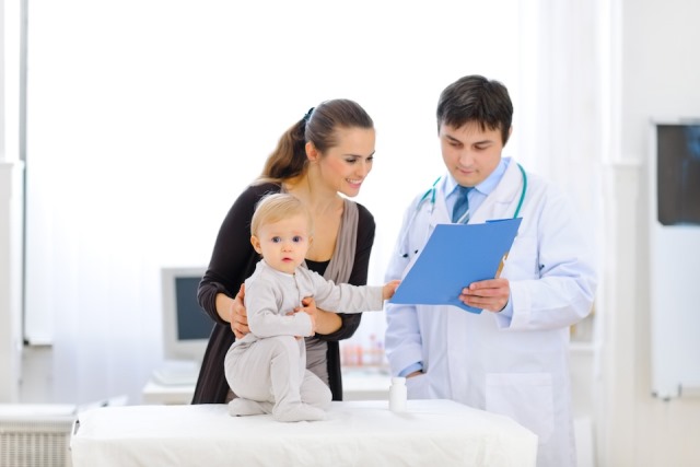 Interested baby touching patients card while pediatrician talking with mother